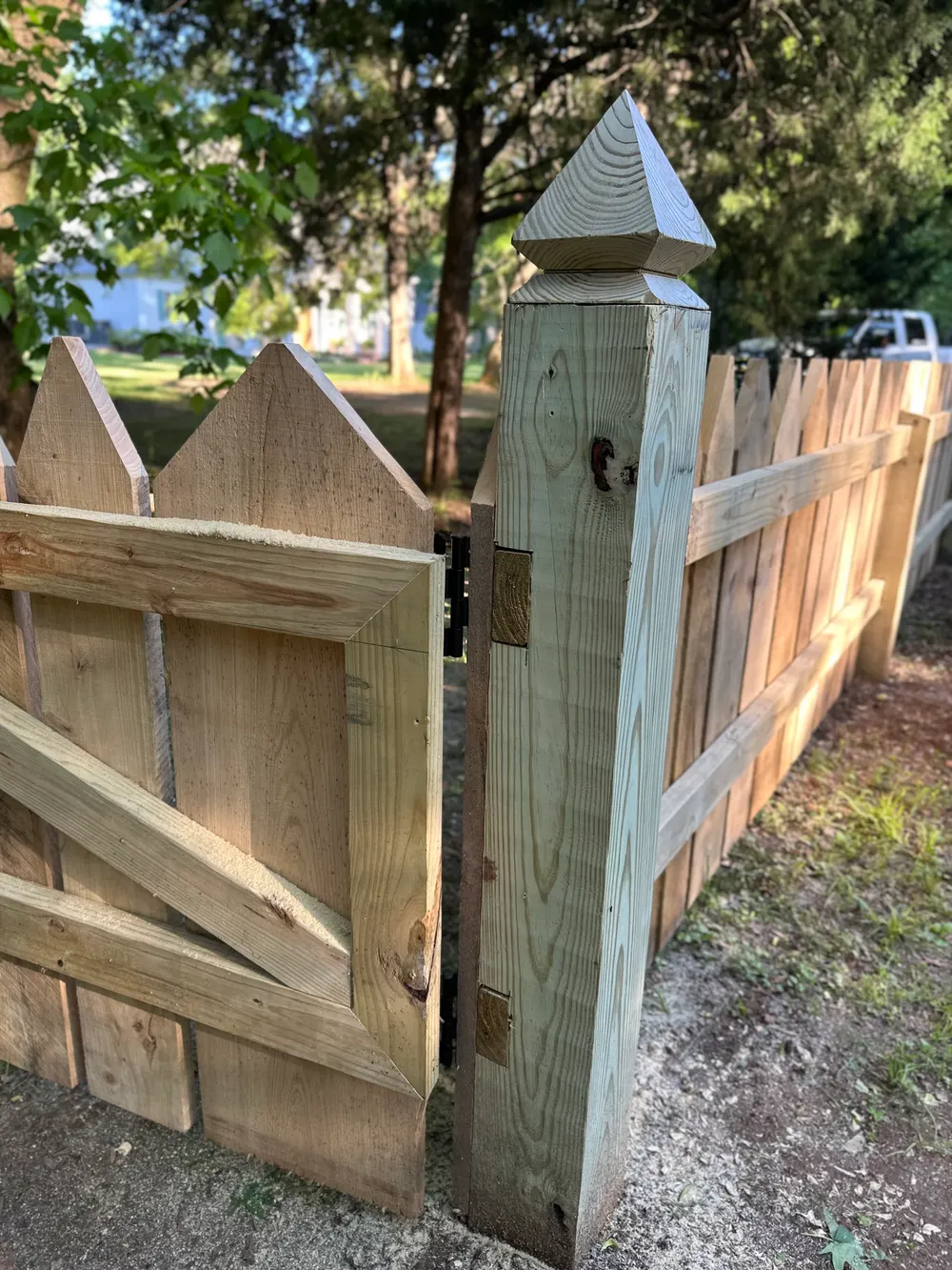 Hand-cut French Gothic point on a gate post beside varied-width wood pickets