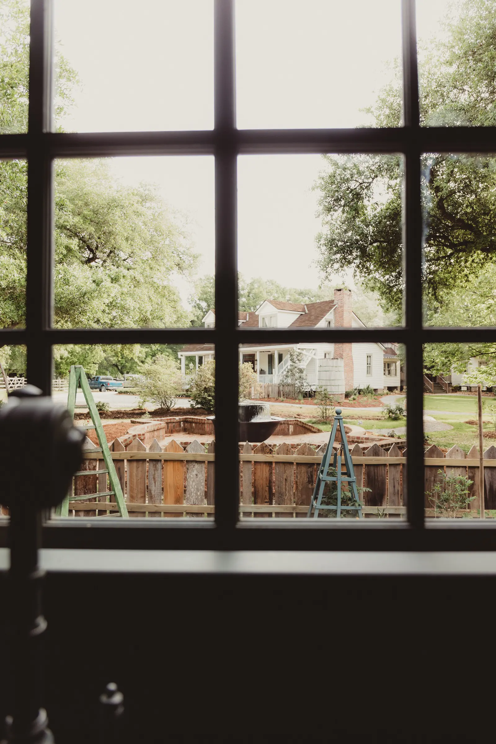 View through a garden building window toward the picket fence and grounds at Beau Bassin